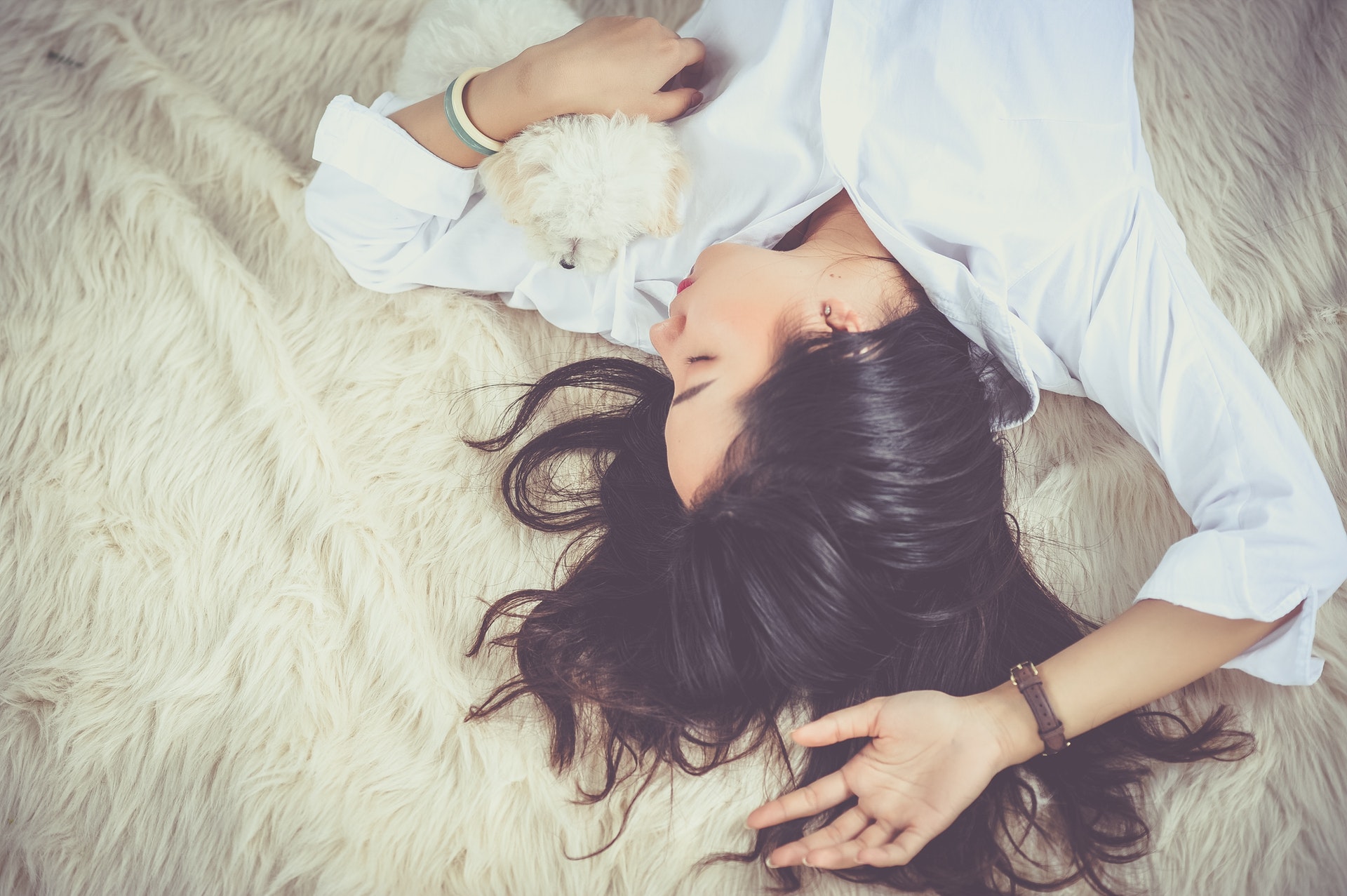 A girl is sleeping while holding her puppy
