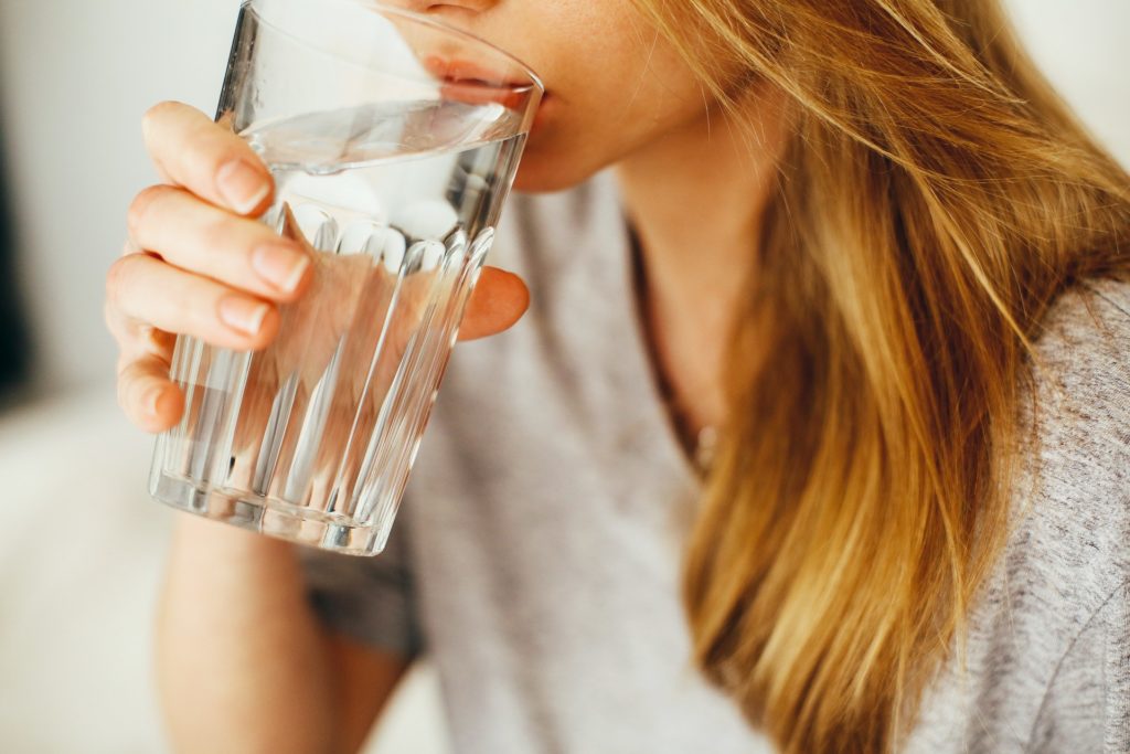 A woman drinks a glass of water