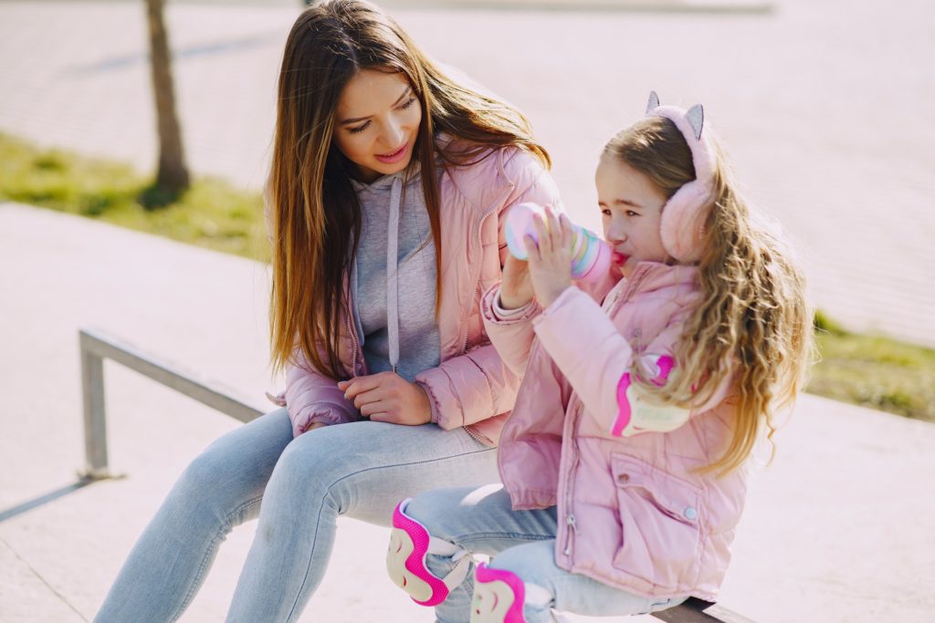 A beautiful girl drinks water with her mother